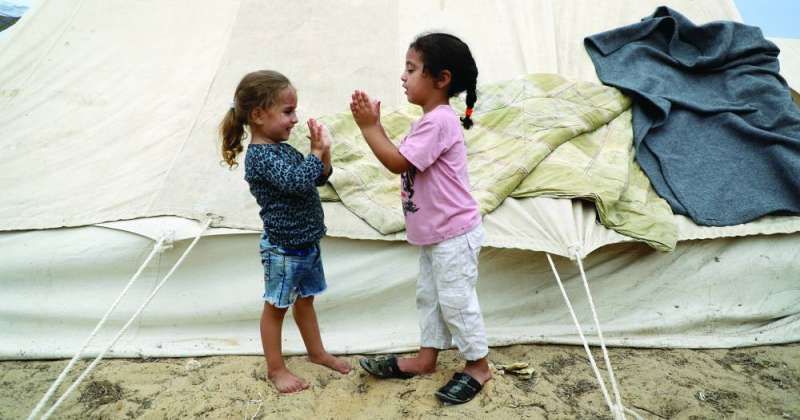 طفلتان جنوب قطاع غزة أمام إحدى الخيم المقدمة للشعب الفلسطيني من الهلال الأحمر الكويتي (شينخوا)